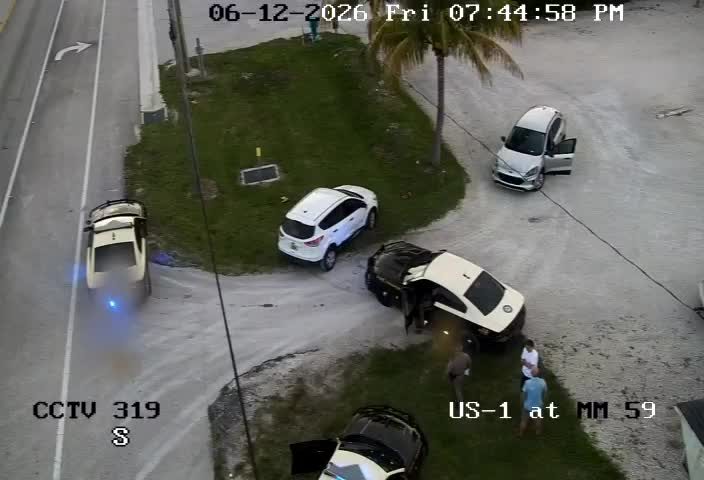 Police officers and civilians gathered around a damaged vehicle on the roadside.