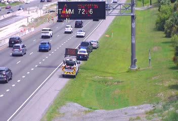 Emergency vehicle and tow truck on the shoulder with traffic backing up.