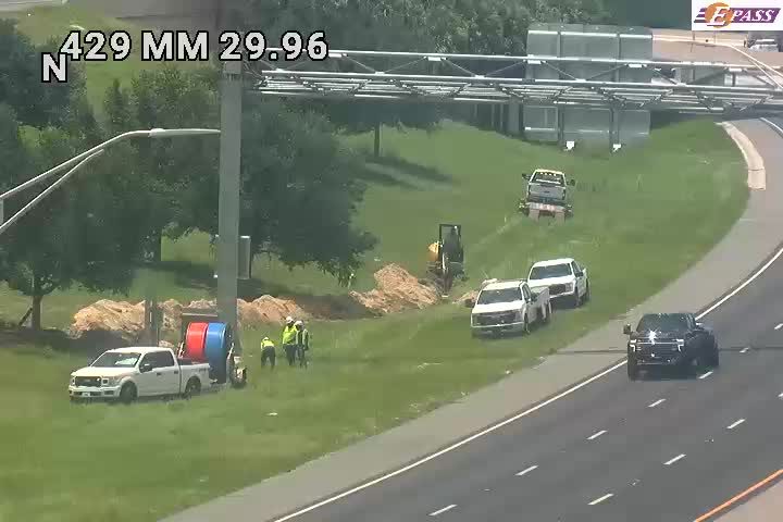 Construction workers and equipment are present on the roadside, indicating ongoing work.