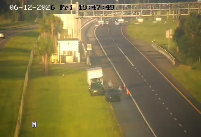 Two vehicles stopped on shoulder with cones and people present.