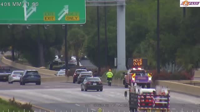 Emergency vehicle with "MOVE OVER" sign and worker present on roadside.