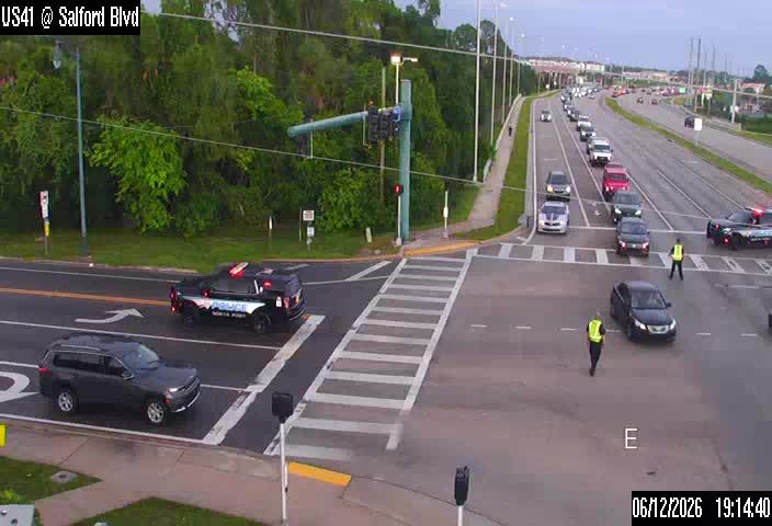 Police vehicles and personnel directing traffic at an intersection.