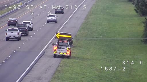 Roadside assistance vehicle with flashing arrow directing traffic on the shoulder.