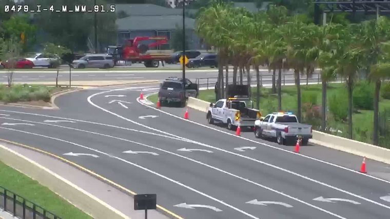 Police and utility trucks on the roadside with cones present.