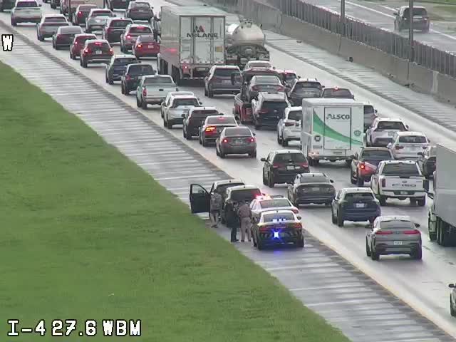 Police and emergency vehicles are present on the highway, indicating an incident.