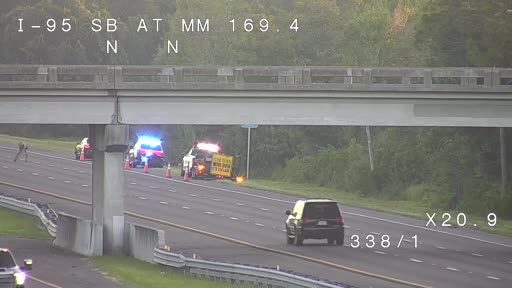 Police car with blue flashing lights and traffic cones on the right shoulder