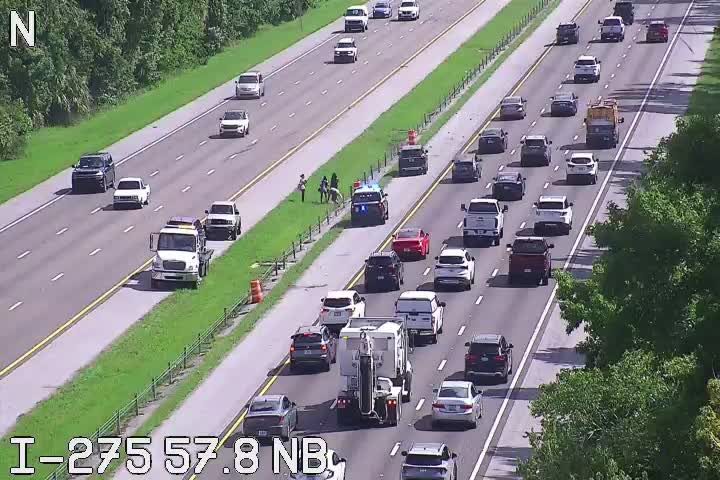 Police car and other vehicles stopped on the shoulder of the highway.