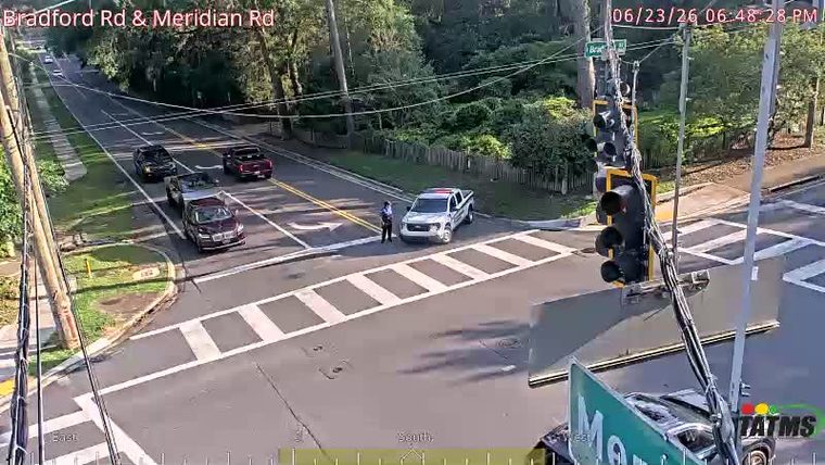 Police car with a person standing next to it in the intersection