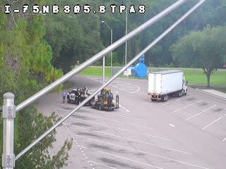 Police and construction vehicle on roadside with a trailer.