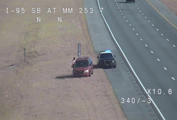 Police car and van pulled over on the shoulder, police lights are on.