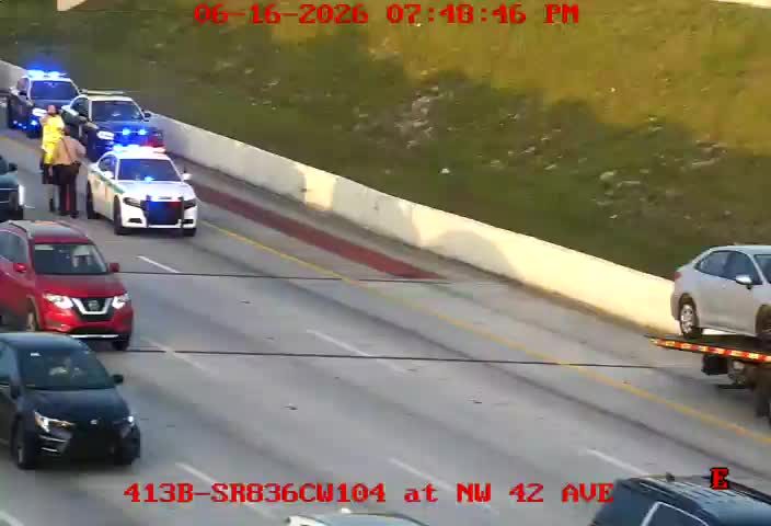 Police cars and personnel on the roadside with a tow truck and vehicle.