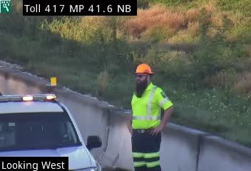 Responder in high-visibility gear and police vehicle on the roadside.