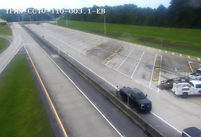 Two white trucks and a trailer are parked on the side of the road.