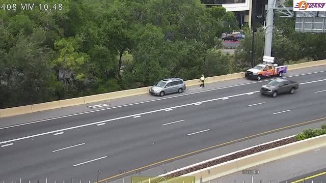 A utility truck and a person are on the shoulder of the highway.