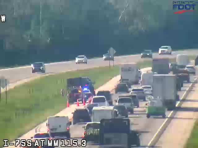 Police and cones on the highway indicate a responder incident.