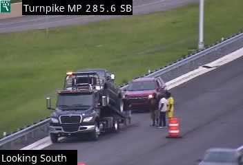 Tow truck and people by orange cone on highway shoulder, Turnpike MP 285.6 SB.