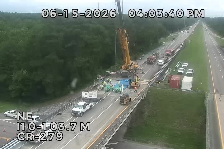 Road construction with crane, workers, and vehicles on the highway.