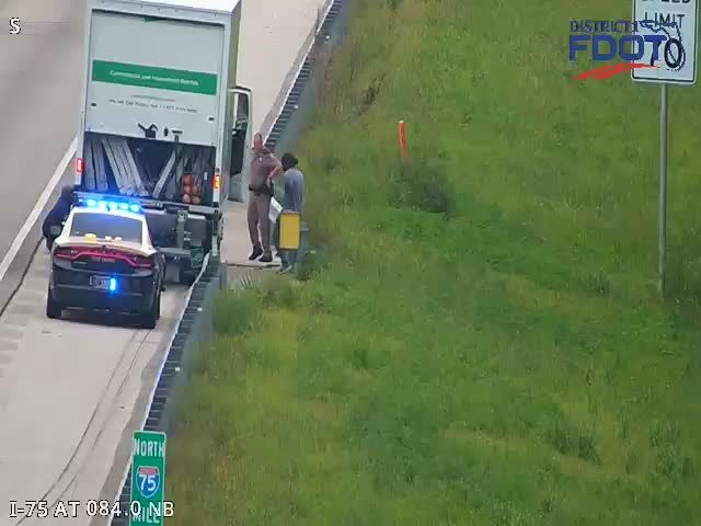 Police car with blue lights on the shoulder next to a box truck
