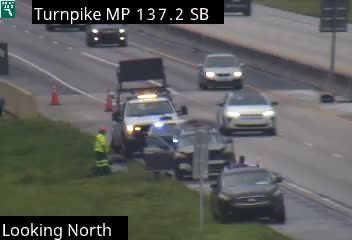 Emergency vehicle and personnel on the side of the highway with traffic cones.
