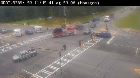 Fire truck and police car at intersection with person standing nearby.