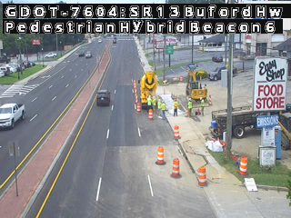 Construction crew and equipment working on the roadway with cones and barriers.
