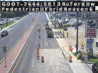 Construction workers and equipment are present on the roadway, indicating ongoing work.