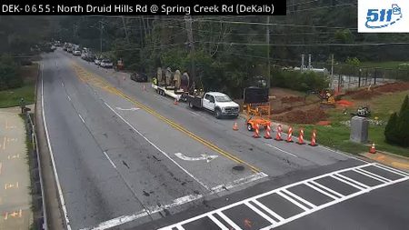 Construction vehicles and cones are present on the roadway, indicating ongoing work.