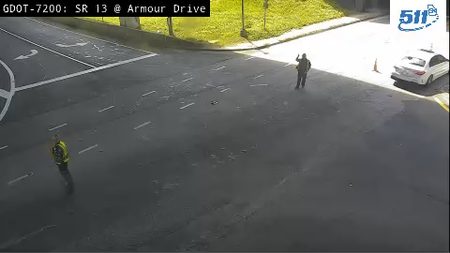 Two people in reflective vests on the roadway, one directing traffic.