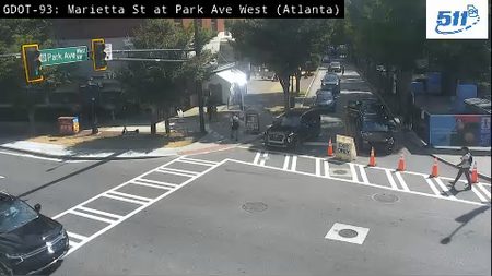 Police officer directing traffic at intersection with cones and a vehicle.