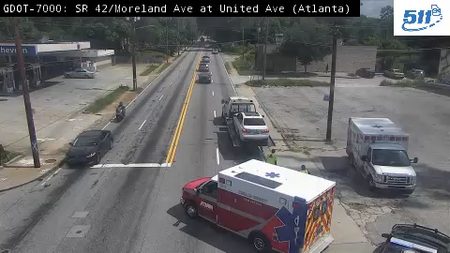 Two ambulances and a tow truck with a car on the right shoulder