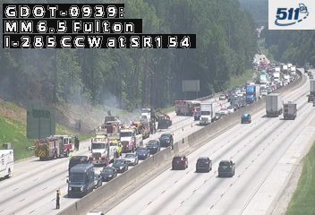 Emergency responders and vehicles at a roadside incident with traffic backup.
