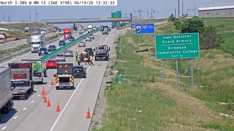 Tow truck with a damaged car on its flatbed, police car, and workers in the right lane