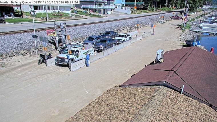 A person in a blue shirt stands near a white truck and concrete barriers.