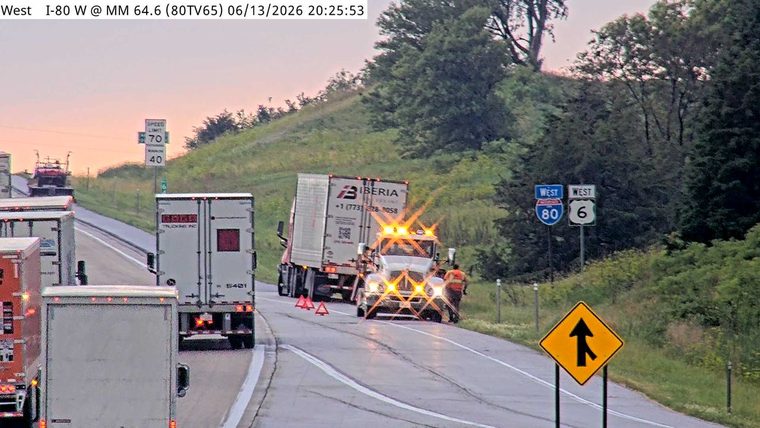 Tow truck with flashing lights and personnel on scene assisting a disabled truck.