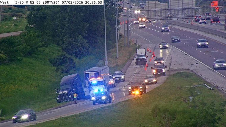 Box truck with blue and red lights on the shoulder, and a person standing nearby
