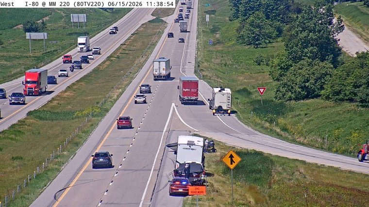 Police and tow truck attending to a vehicle with a trailer on the shoulder.