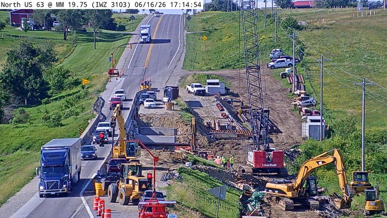 Construction zone with workers and heavy machinery present on the roadway.