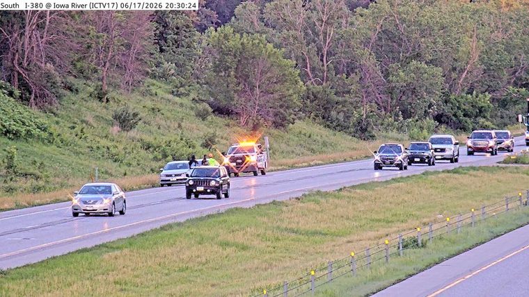 Tow truck with flashing lights and personnel on the roadside.