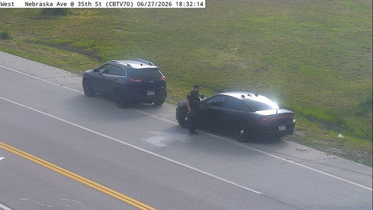 Police officer standing next to a police car on the right shoulder
