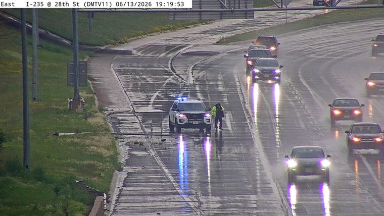 Police car with lights on and officer present on wet highway.