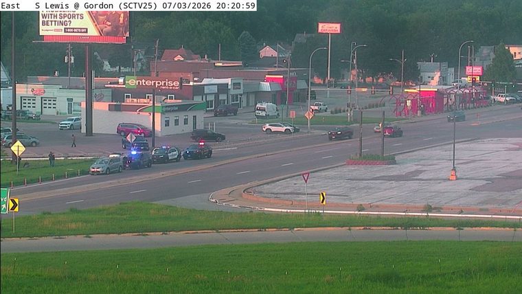 Three police cars and a civilian vehicle stopped in the roadway