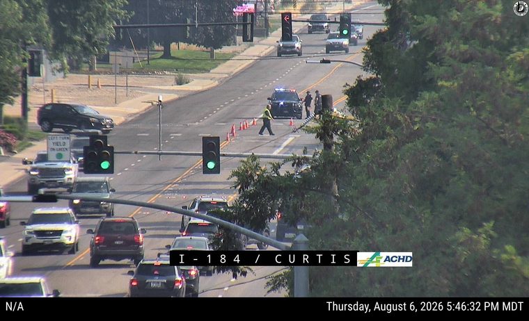 Police car with lights on in the roadway with cones and personnel present