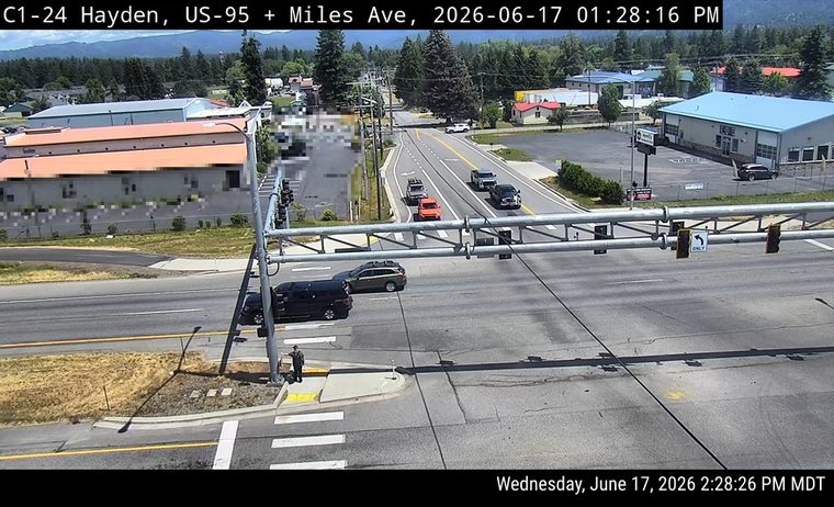 Police officer directing traffic at intersection with a black SUV stopped nearby.
