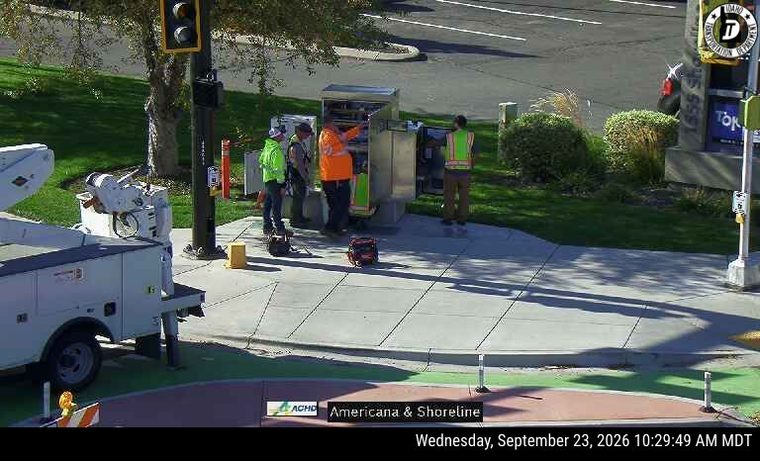 Four workers with high-visibility vests near equipment on the sidewalk