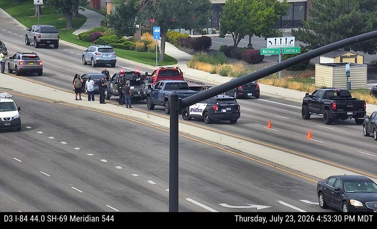 Police car and tow truck with people around a car on the right shoulder