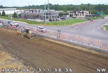 Construction workers and equipment are present on the roadway.