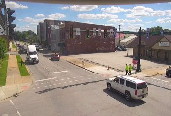 Two individuals in safety vests appear to be responding to something near traffic cones.