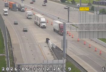 Debris on the roadway, traffic cones present, traffic moving slowly.