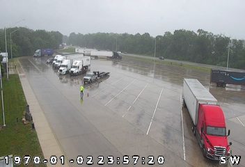 Person in reflective vest on wet roadway, possibly directing traffic.