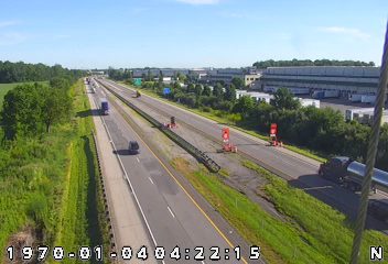 Emergency responders with cones and equipment on the highway shoulder.
